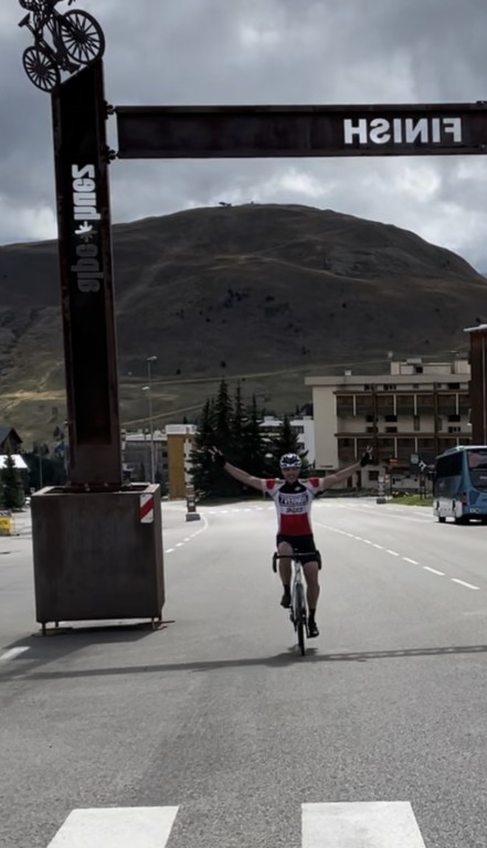 biker with arms out crossing finish line